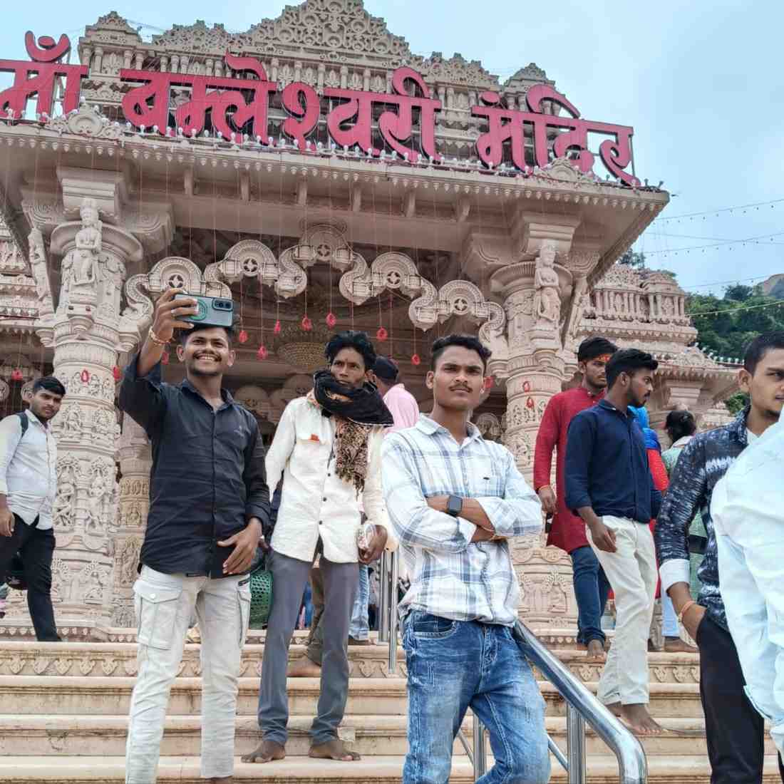 Tourists posing in front of the ornate white stone entrance of Ma Bamleshwari Temple in Dongargarh, Chhattisgarh.