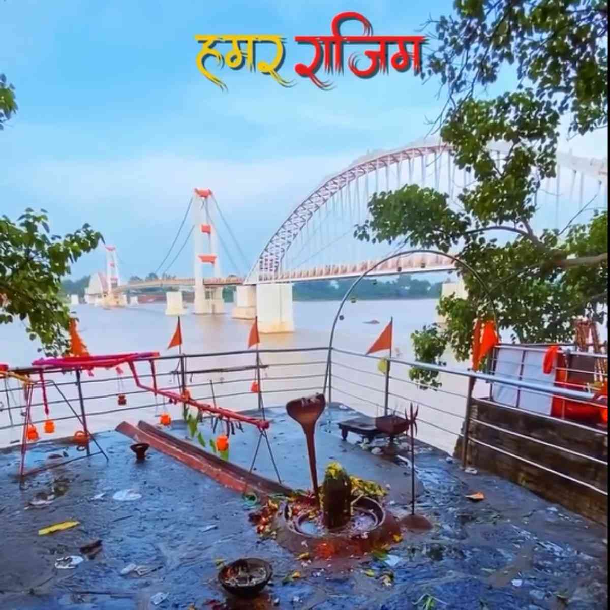 Scenic view of a riverfront Shiva Linga shrine at Rajim Triveni Sangam with the modern Lakshman Jhula suspension bridge in the background.